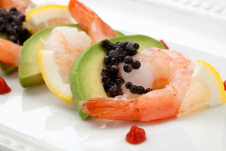 Close up of delicious appetizer shrimp cocktail with black caviar. Garnished with avocado, lemon, and horseradish cocktail sauce for seafood. Elite food.の写真素材