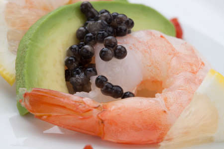 Close up of delicious appetizer shrimp cocktail with black caviar. Garnished with avocado, lemon, and horseradish cocktail sauce for seafood. Elite food.の写真素材