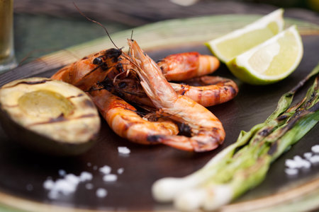 Plate of grilled shrimps, avocado, and scallions. Served with lime ans sea salt. Outside dinner in a garden.の写真素材