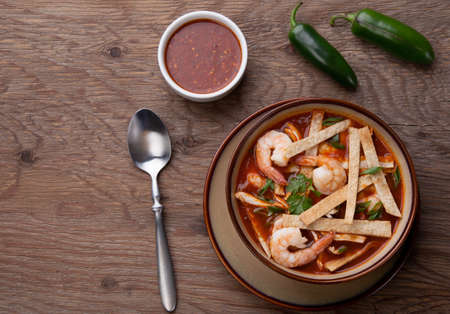 Bowl of hot delicious shrimp tortilla soup garnished with green onion, fresh cilantro, and salsa.の写真素材