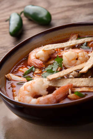 Bowl of hot delicious shrimp tortilla soup garnished with green onion, fresh cilantro, and salsa.の写真素材