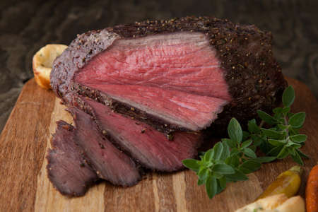 Peppercorn roasic style roast beef with herbed Yorkshire puddings garnished with caramelized carrots.の写真素材