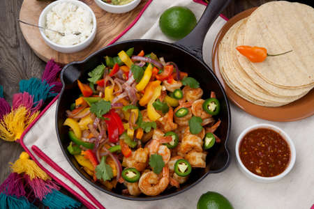 Shrimp fajitas with bell pepper, onion, and jalapeno in cast iron skillet ready to be served. Guacamole, salsa, and tortillas.の写真素材