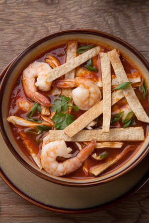 Bowl of hot delicious shrimp tortilla soup garnished with green onion, fresh cilantro, and salsa.の写真素材