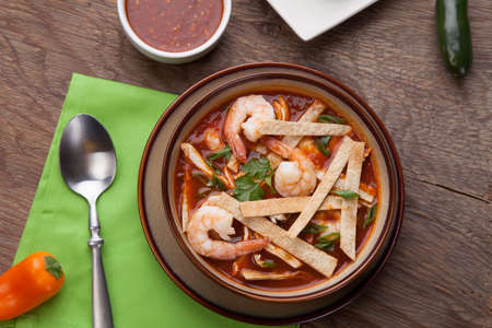 Bowl of hot delicious shrimp tortilla soup garnished with green onion, fresh cilantro, and salsa.の写真素材