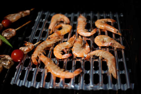 Whole grilled shrimps on grill with grilled vegetables on skewers. Outside dinner in a garden.の写真素材