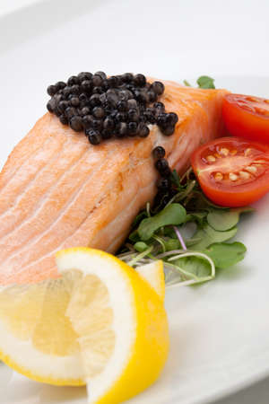 Close up of delicious pan fried salmon with fresh black caviar, tomatoes, and microgreens salad. Elite food.の写真素材