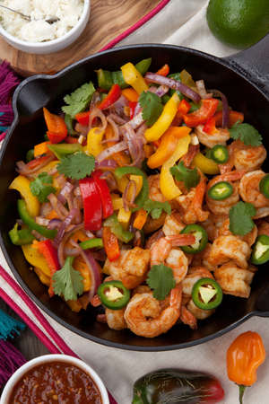 Shrimp fajitas with bell pepper, onion, and jalapeno in cast iron skillet ready to be served. Guacamole, salsa, and tortillas.の写真素材