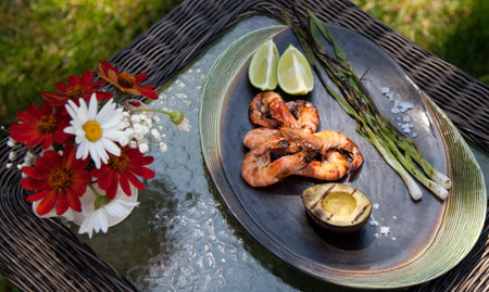Plate of grilled shrimps, avocado, and scallions. Served with lime ans sea salt. Outside dinner in a...