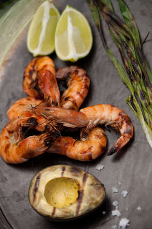 Plate of grilled shrimps, avocado, and scallions. Served with lime ans sea salt. Outside dinner in a garden.の写真素材