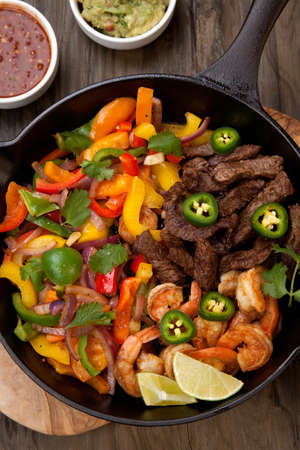 Beef fajitas with bell pepper, onion, and avocado in cast iron skillet ready to be served.の写真素材