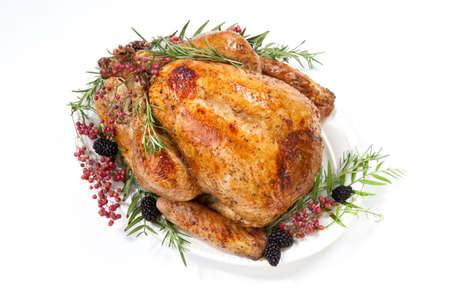 Thanksgiving pepper roasted turkey garnished with blackberry and pink peppercorn on white.の写真素材