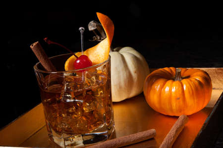 Closeup of Old Fashioned Whiskey Cocktail at a bar ready to be served. Mini pumpkins and cinnamon sticks. Fall Drinks series.の写真素材