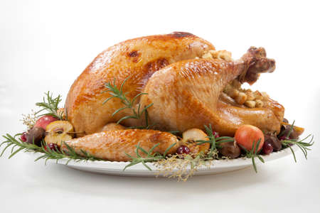 Garnished roasted turkey with grab apples, sweet chestnut, and cranberry over white backgroundの写真素材