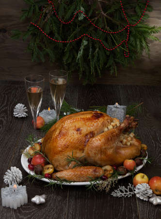 Garnished roasted Christmas turkey with grab apples, sweet chestnut, cranberry, Christmas ornaments, candles, and pine cones.の写真素材