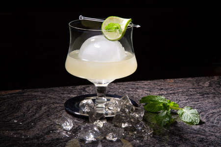 Close-up of white mint spritzer cocktail at bar ready to be served. Ice and fresh mint on bar countertop.の写真素材