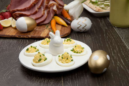 Plate of deviled eggs sidedish for delicious spicey roasted Easter ham dish, asparagus, butternut squash with green peas, baby carrots, strawberries, and Easter decoration.の写真素材