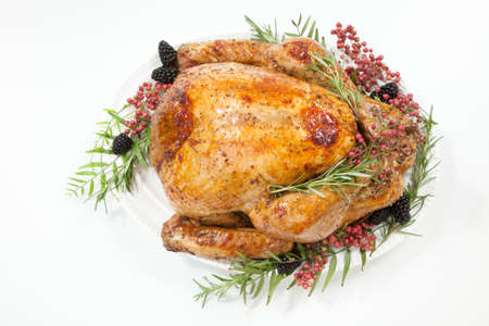 Thanksgiving pepper roasted turkey garnished with blackberry and pink peppercorn on white.の写真素材