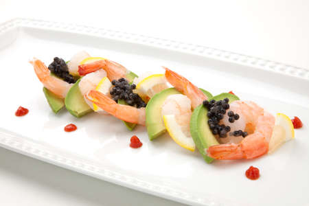 Close up of delicious appetizer shrimp cocktail with black caviar. Garnished with avocado, lemon, and horseradish cocktail sauce for seafood. Elite food.の写真素材