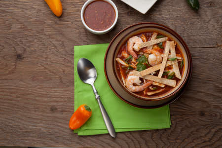 Bowl of hot delicious shrimp tortilla soup garnished with green onion, fresh cilantro, and salsa.の写真素材