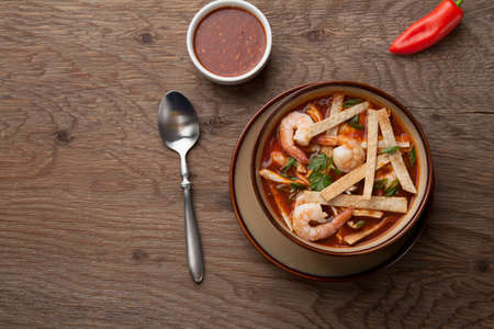 Bowl of hot delicious shrimp tortilla soup garnished with green onion, fresh cilantro, and salsa.の写真素材