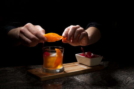 Whiskey based cocktail - closeup of bartender hands preparing Old Fashioned Whiskey Cocktail on bar counter.の写真素材