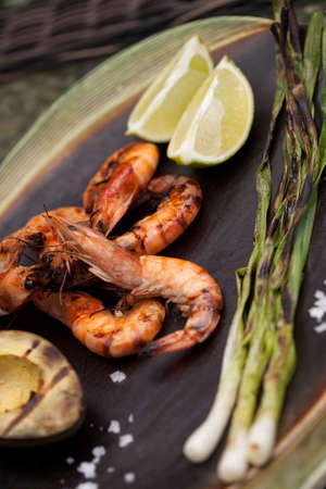 Plate of grilled shrimps, avocado, and scallions. Served with lime ans sea salt. Outside dinner in a garden.の写真素材