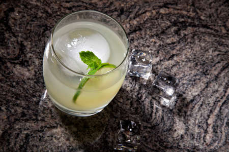 Close-up of white mint spritzer cocktail at bar ready to be served. Ice and fresh mint on bar countertop.の写真素材