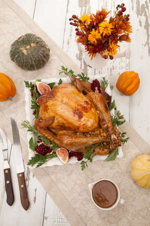 Garnished traditional roasted turkey for Thanksgiving, garnished with fresh figs, pomegranate, and herbs. Pumpkins, fall flowers, and decorations.の写真素材