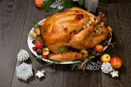 Garnished roasted Christmas turkey with grab apples, sweet chestnut, cranberry, Christmas ornaments, candles, and pine cones.の写真素材