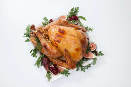 Garnished traditional roasted turkey, garnished with fresh figs, pomegranate, and herbs. On white background.の写真素材