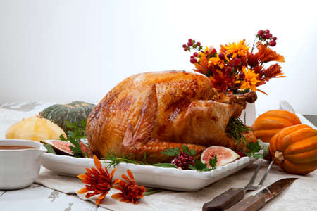 Garnished traditional roasted turkey for Thanksgiving, garnished with fresh figs, pomegranate, and herbs. Pumpkins, fall flowers, and decorations.の写真素材