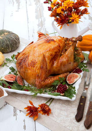Garnished traditional roasted turkey for Thanksgiving, garnished with fresh figs, pomegranate, and herbs. Pumpkins, fall flowers, and decorations.の写真素材
