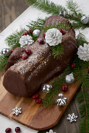 Traditional Christmas chocolate yule log cake with cranberry, Christmas ornamets, and decorations.の写真素材