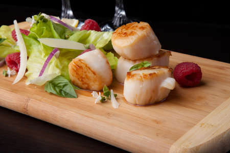 Close up of delicious savory fried scallops salad with fresh raspberry, basil, green lettuce, and red onion.の写真素材