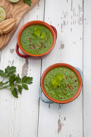 Two bowls of green gazpacho soup with boiled eggs - appetizer for Easter brunch. Easter eggs and flowers.の写真素材