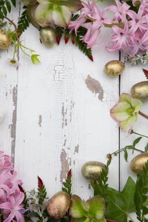 Flowers and eggs full floral frame over rustic wooden boards, background for Easter. Center copy space.の写真素材