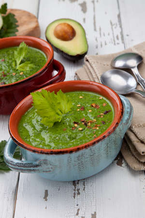 Two bowls of green gazpacho soup with boiled eggs - appetizer for Easter brunch. Easter eggs and flowers.の写真素材