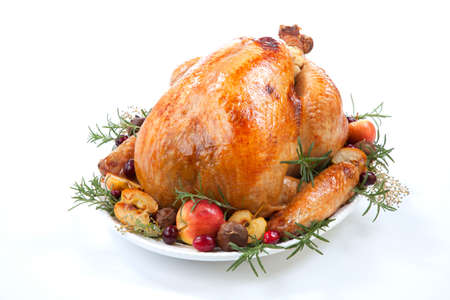 Garnished roasted turkey with grab apples, sweet chestnut, and cranberry over white backgroundの写真素材