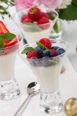 Closeup of Easter Vanilla Panna Cotta Dessert garnished with fresh strawberry, blueberry, and raspberryの写真素材