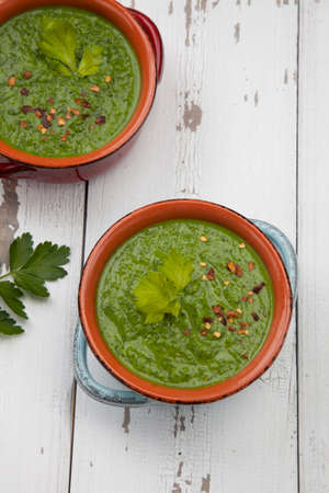 Two bowls of green gazpacho soup with boiled eggs - appetizer for Easter brunch. Easter eggs and flowers.の写真素材