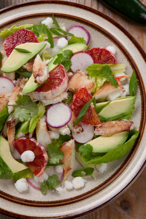 Fusion of Mexican cuisine and a traditional seafood crab salad. Closeup of Blood Orange Crab Posole Salad with fresh cooked Dungeness crab meat, avocado, radish, Romaine lettuce, and white hominy.の写真素材