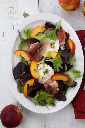 Closeup of Prosciutto peach salad with rresh Mozzarella plate mixed with spring greens. Freash peaches.の写真素材