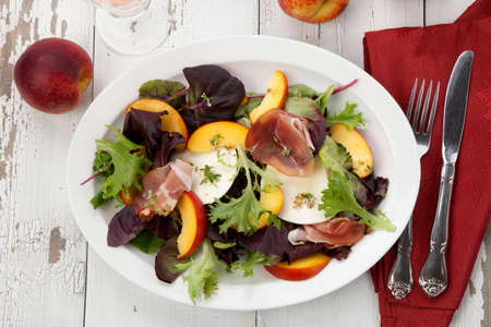 Closeup of Prosciutto peach salad with rresh Mozzarella plate mixed with spring greens. Freash peaches.の写真素材