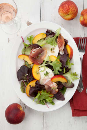 Closeup of Prosciutto peach salad with rresh Mozzarella plate mixed with spring greens. Freash peaches.の写真素材
