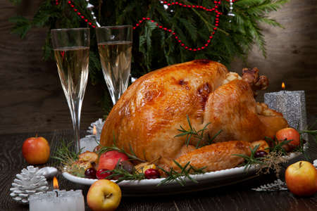 Garnished roasted Christmas turkey with grab apples, sweet chestnut, cranberry, Christmas ornaments, candles, and pine cones.の写真素材