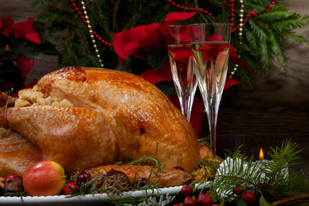 Garnished roasted Christmas turkey with grab apples, sweet chestnut, cranberry, Christmas ornaments, candles, and pine cones.の写真素材