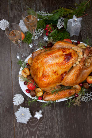 Garnished roasted Christmas turkey with grab apples, sweet chestnut, cranberry, Christmas ornaments, candles, and pine cones.の写真素材