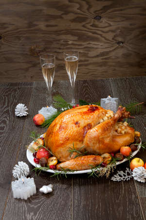 Garnished roasted Christmas turkey with grab apples, sweet chestnut, cranberry, Christmas ornaments, candles, and pine cones.の写真素材