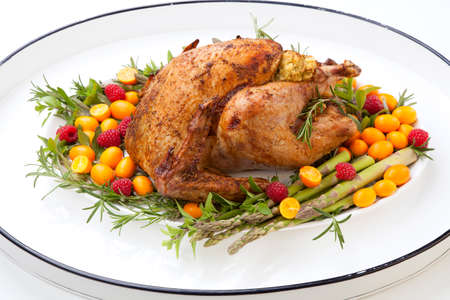 citrus glazed roasted Turkey on white tray for Thanksgiving celebration garnished with kumquat, raspberry, asparagus, oregano, and fresh rosemary twigs. Mini pumpkins.の写真素材